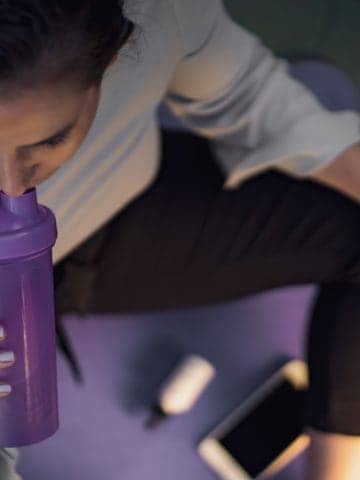 woman sipping on purple shaker