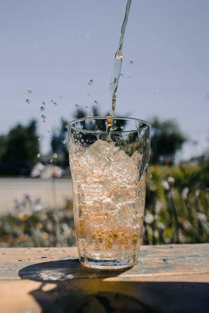 clear drinking glass with ice cubes and flowing liquid during daytime