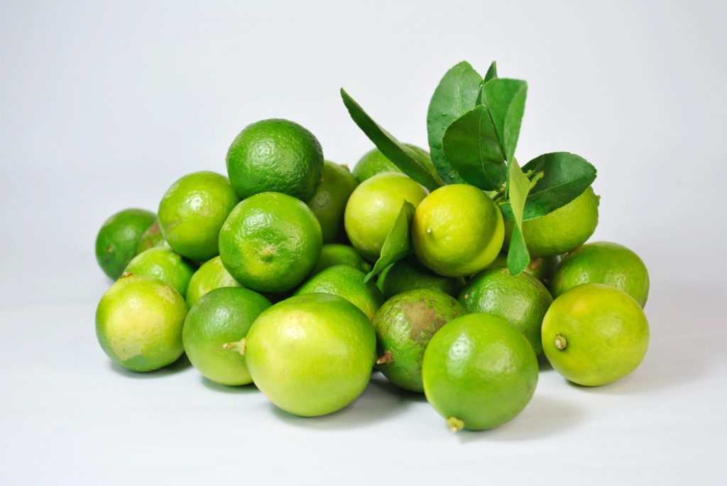 green lemon fruit on white surface
